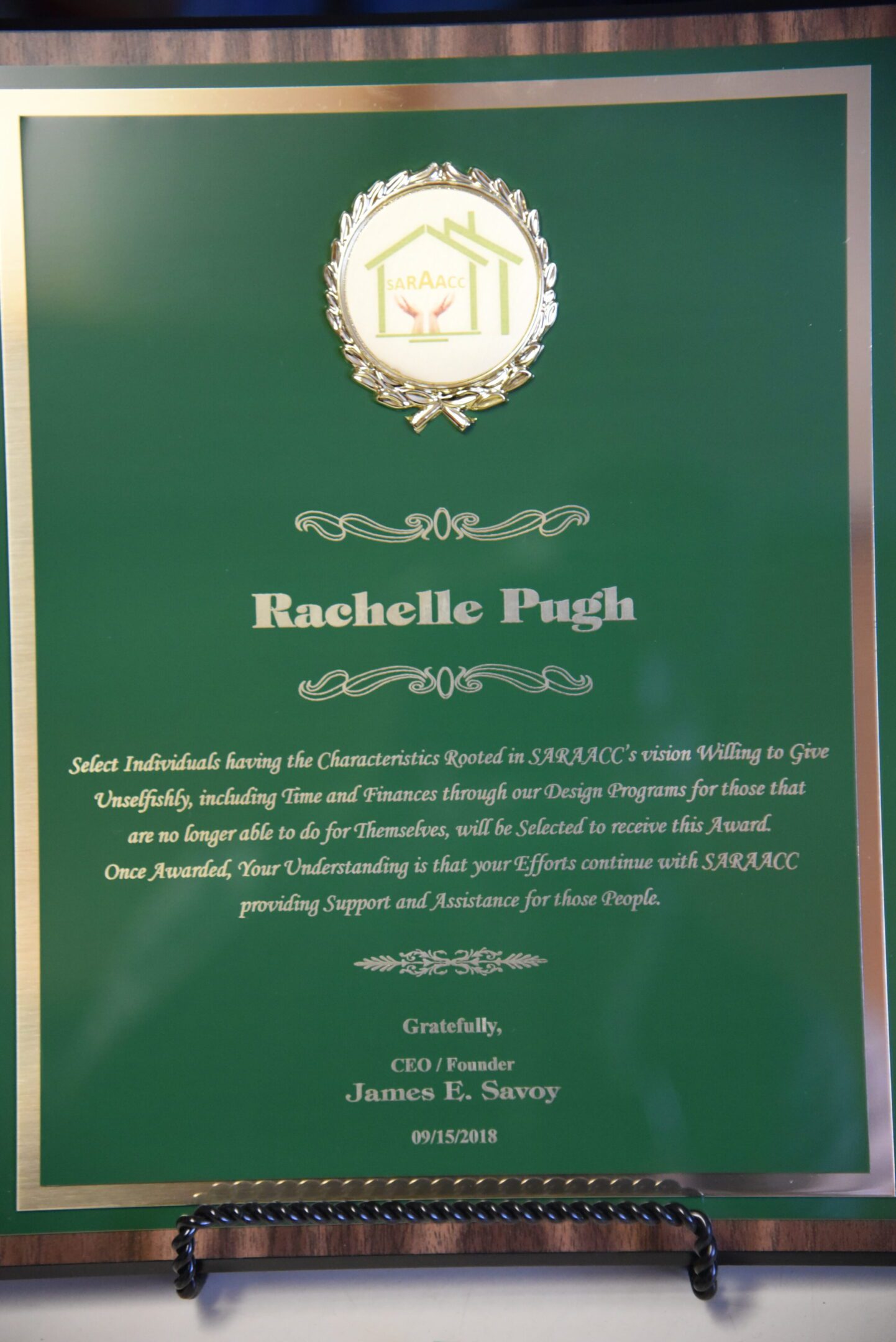 Green award plaque with text and logo.