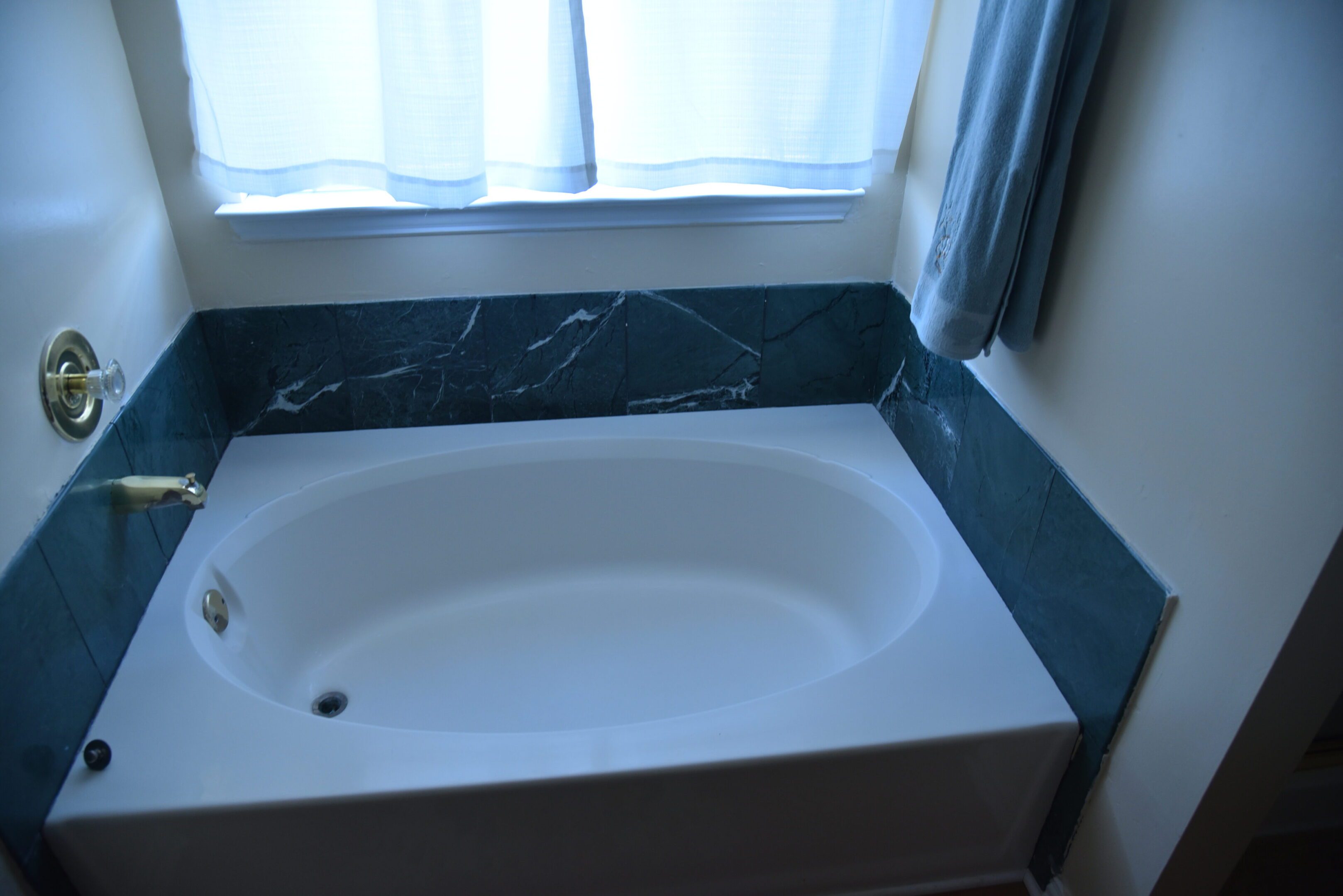 Bathtub with marble tiles and curtain.