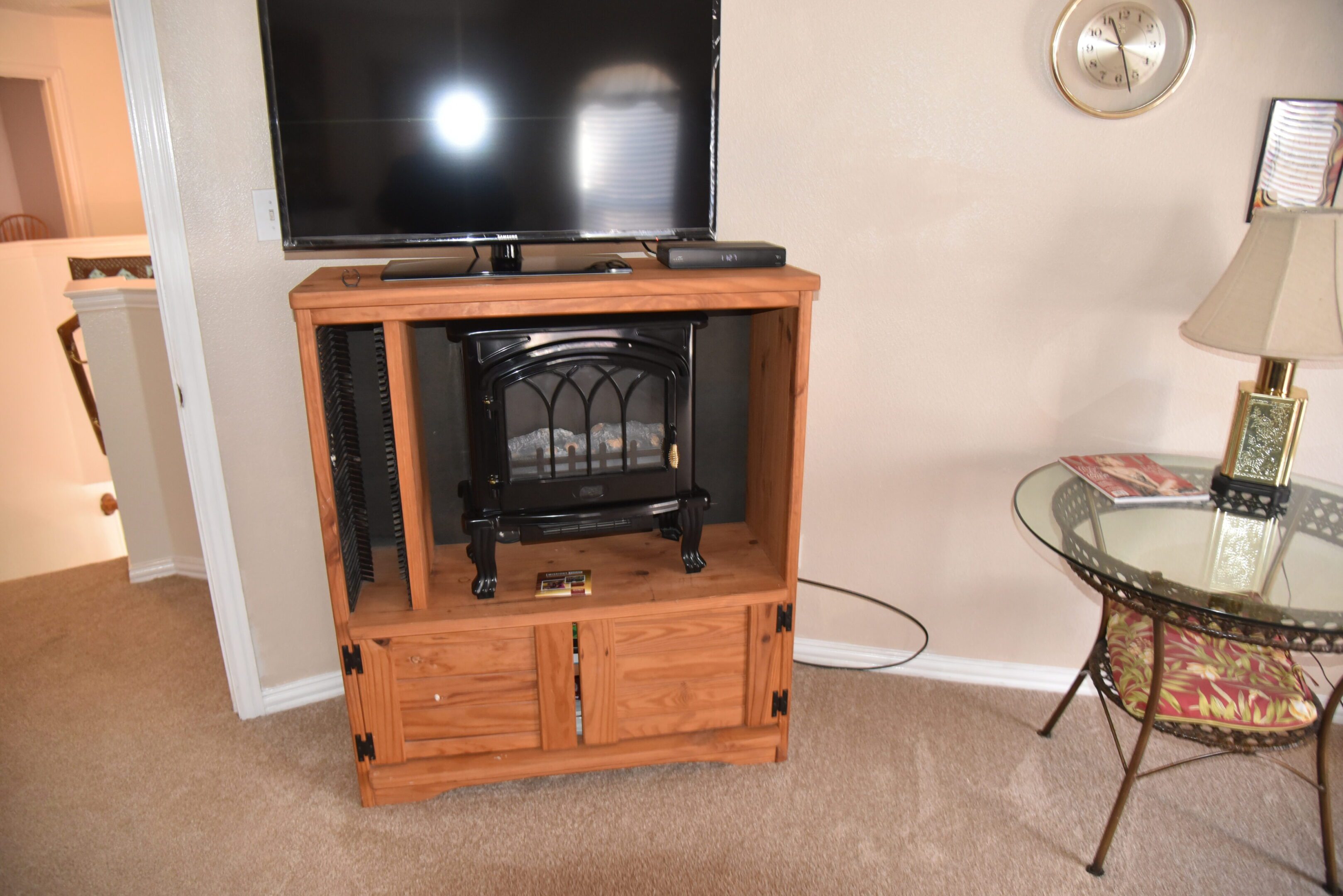 TV on wooden stand with electric fireplace.