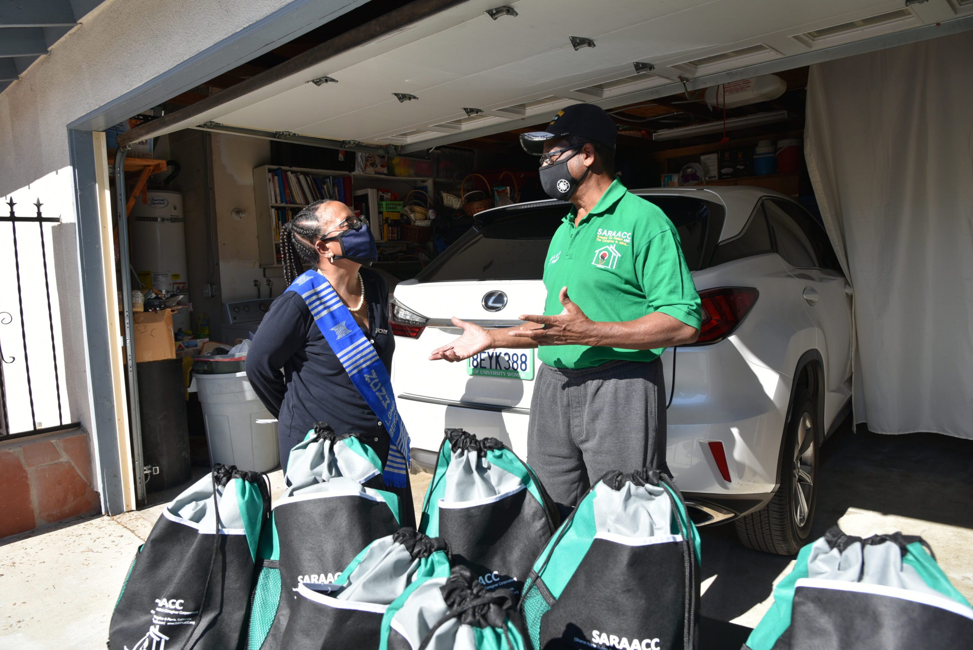 Two people talking near car and bags.