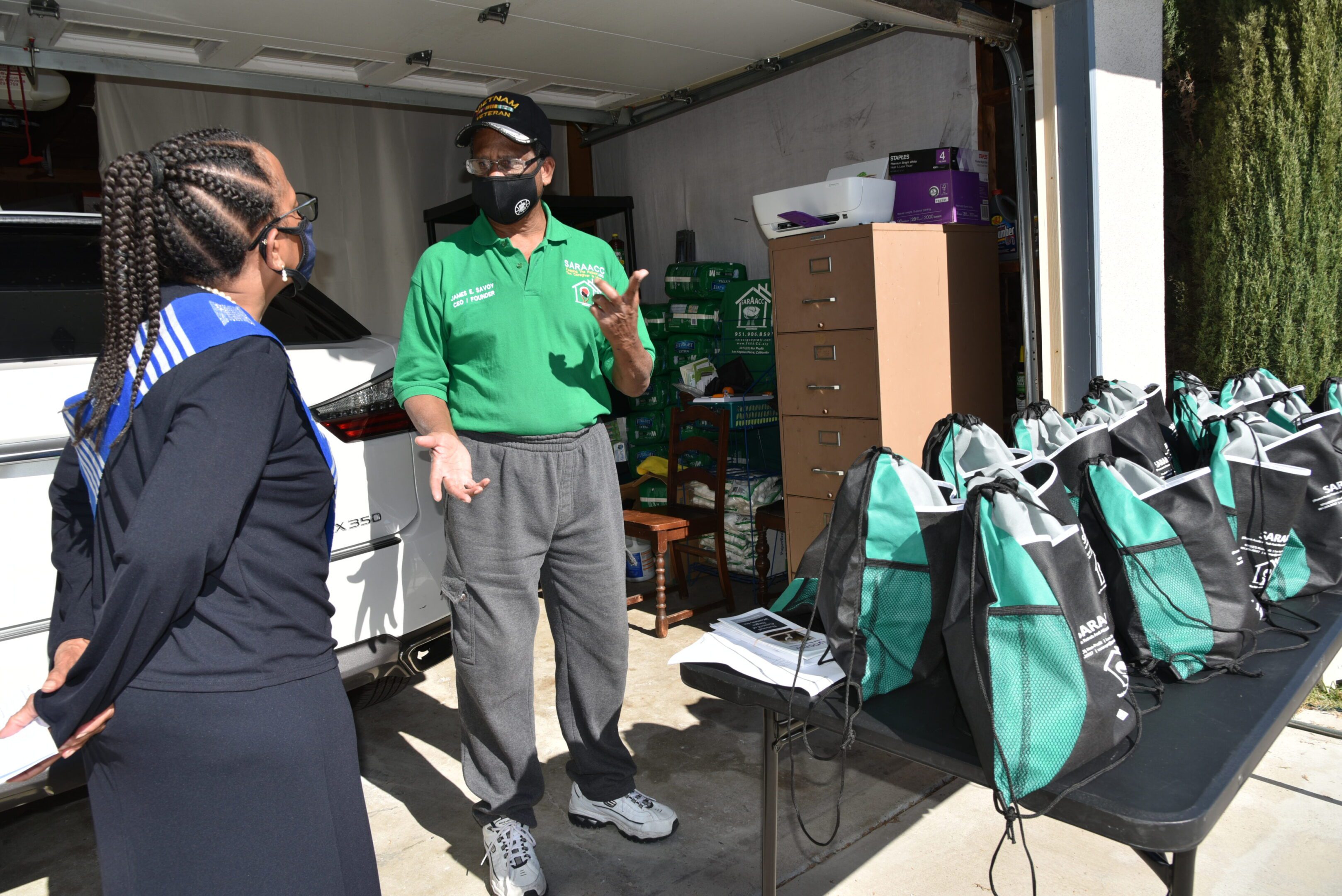 Two people talking near bags in garage.