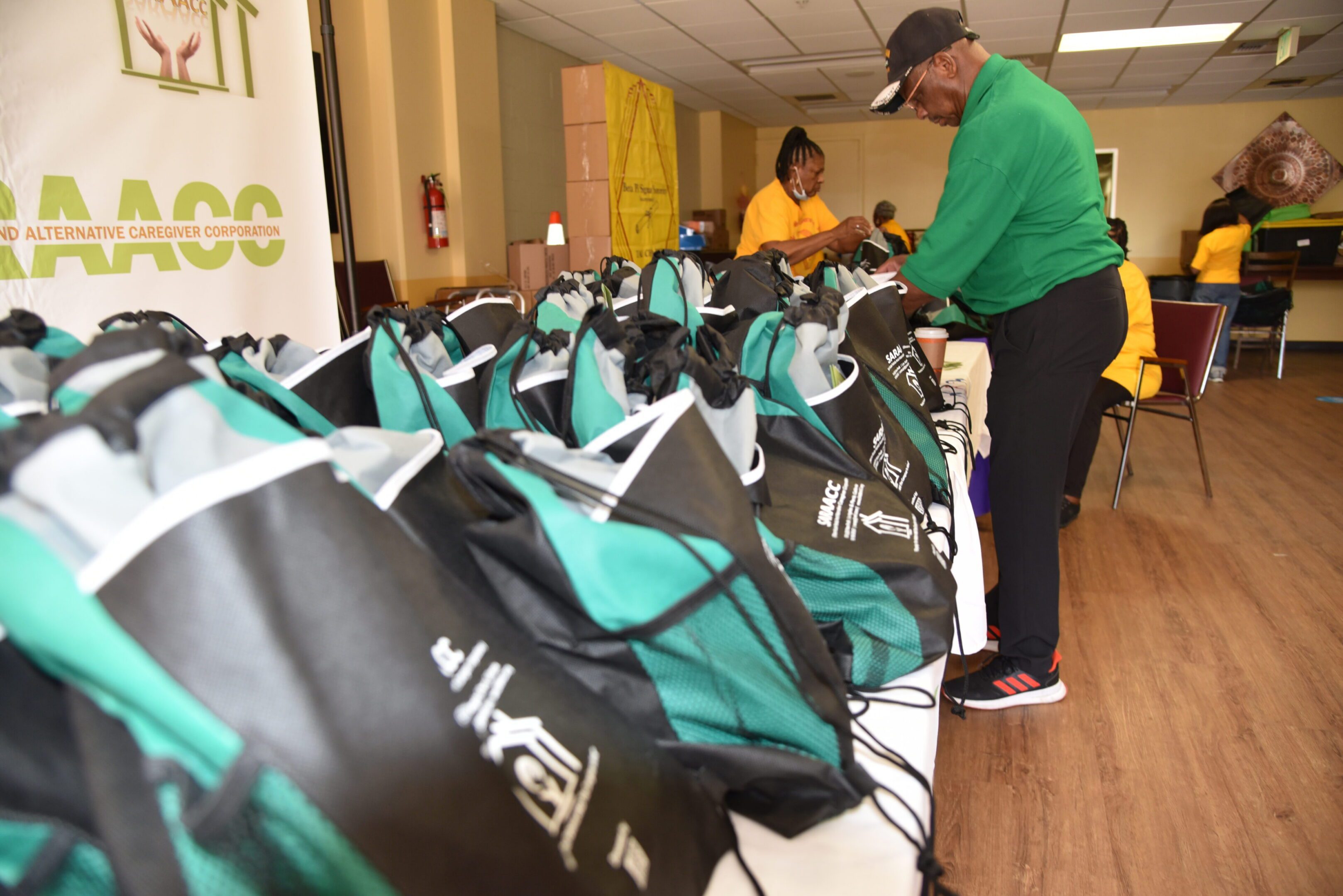 People organizing green and black drawstring bags.