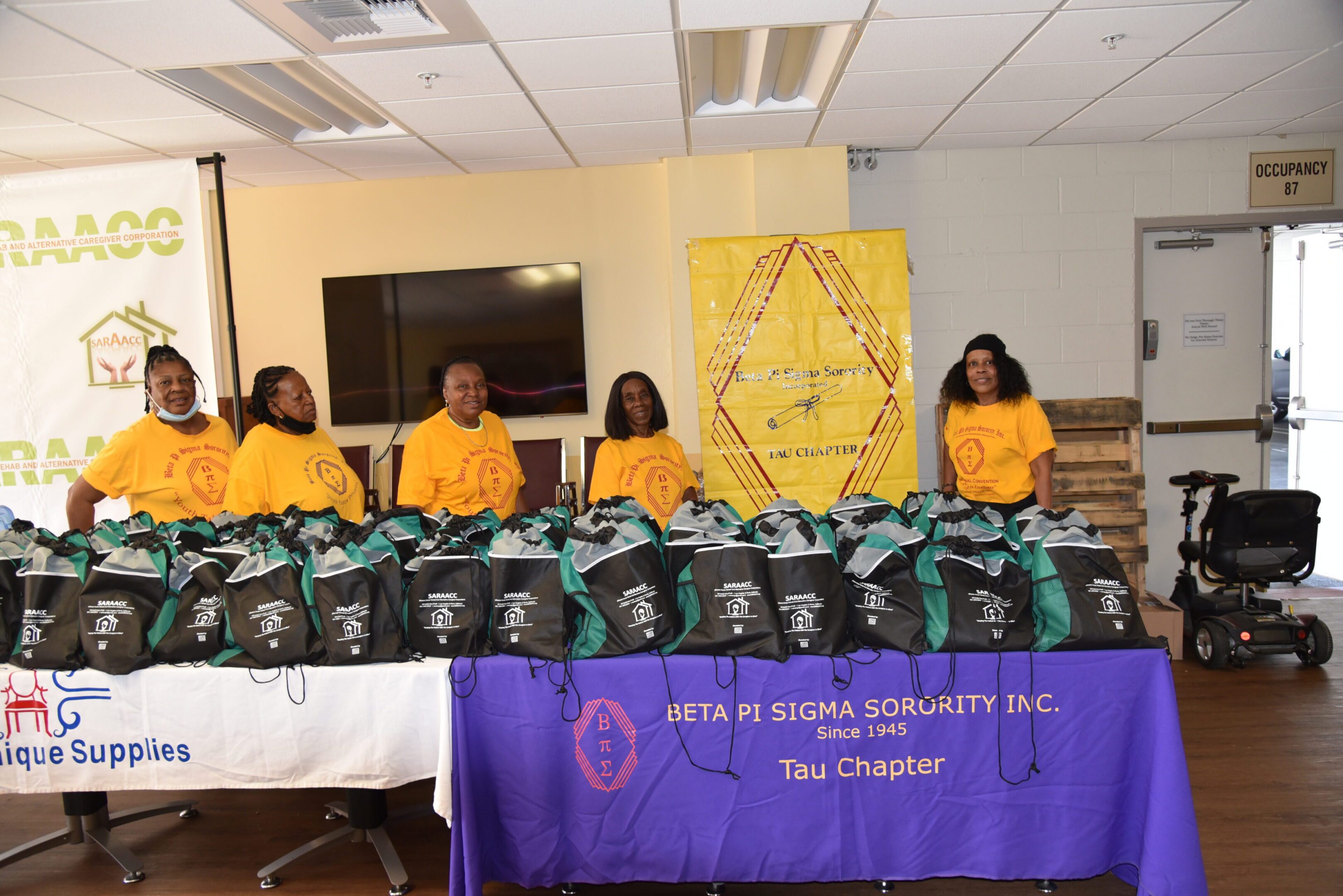 Group posing with donation bags indoors.