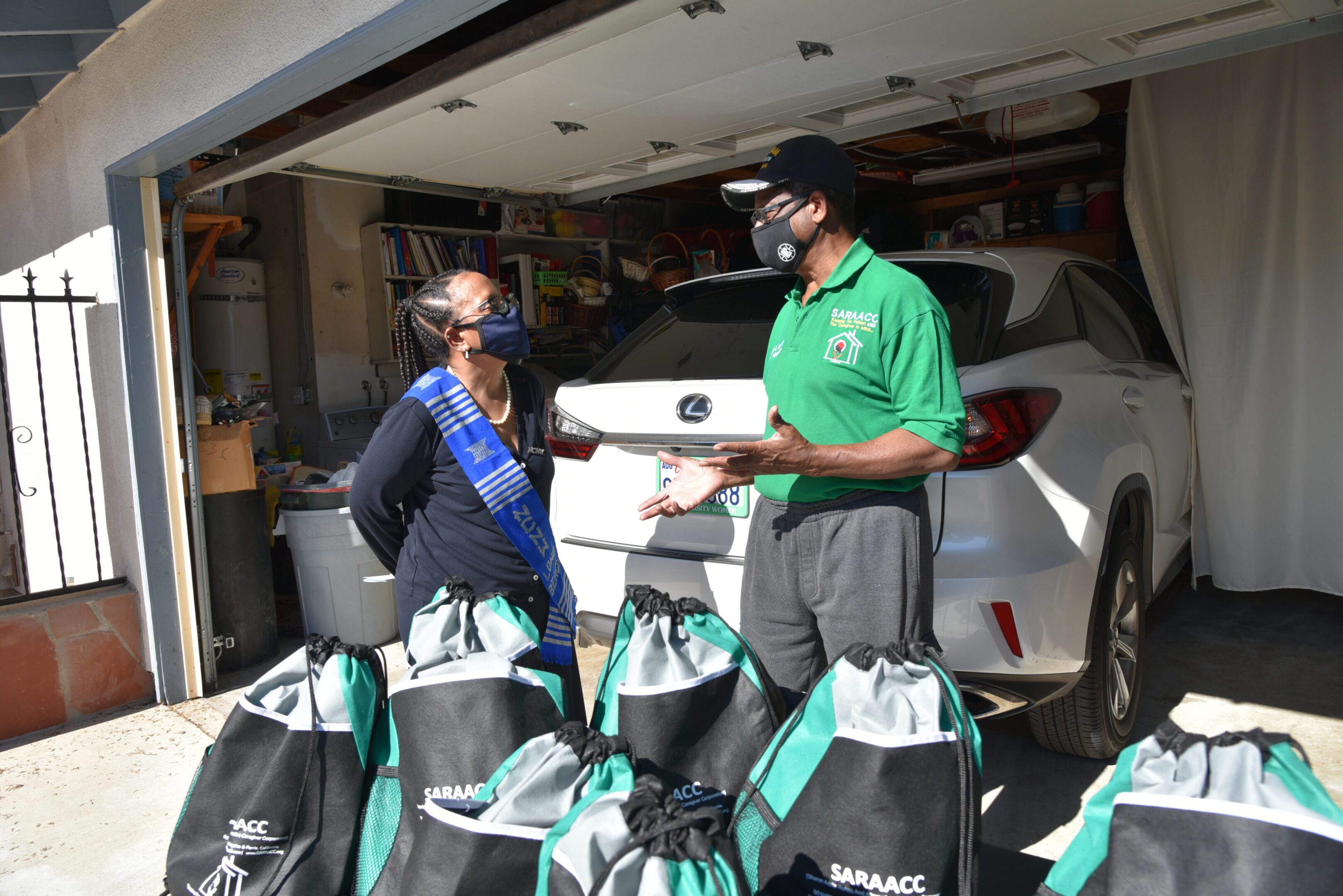 Two people distributing bags from a garage.