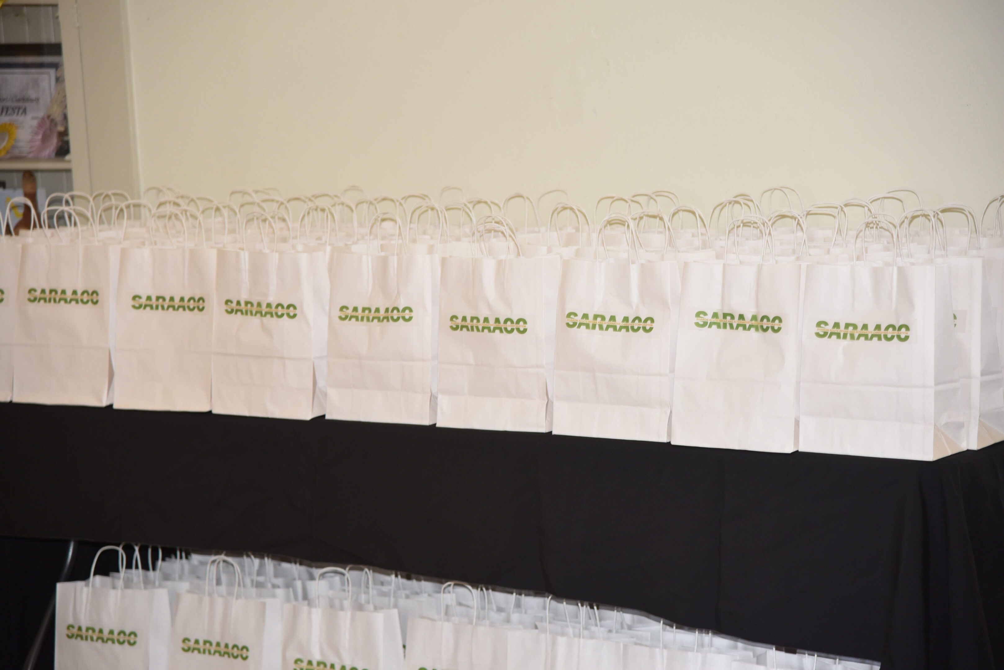 White gift bags with green "SARAAOC" text.