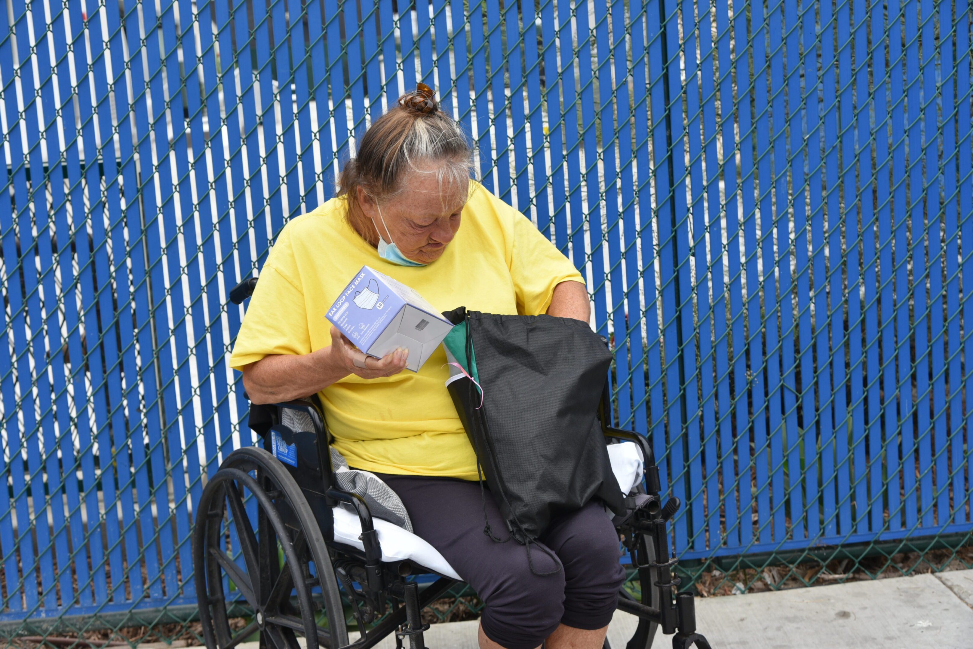Woman in wheelchair with box and bag.