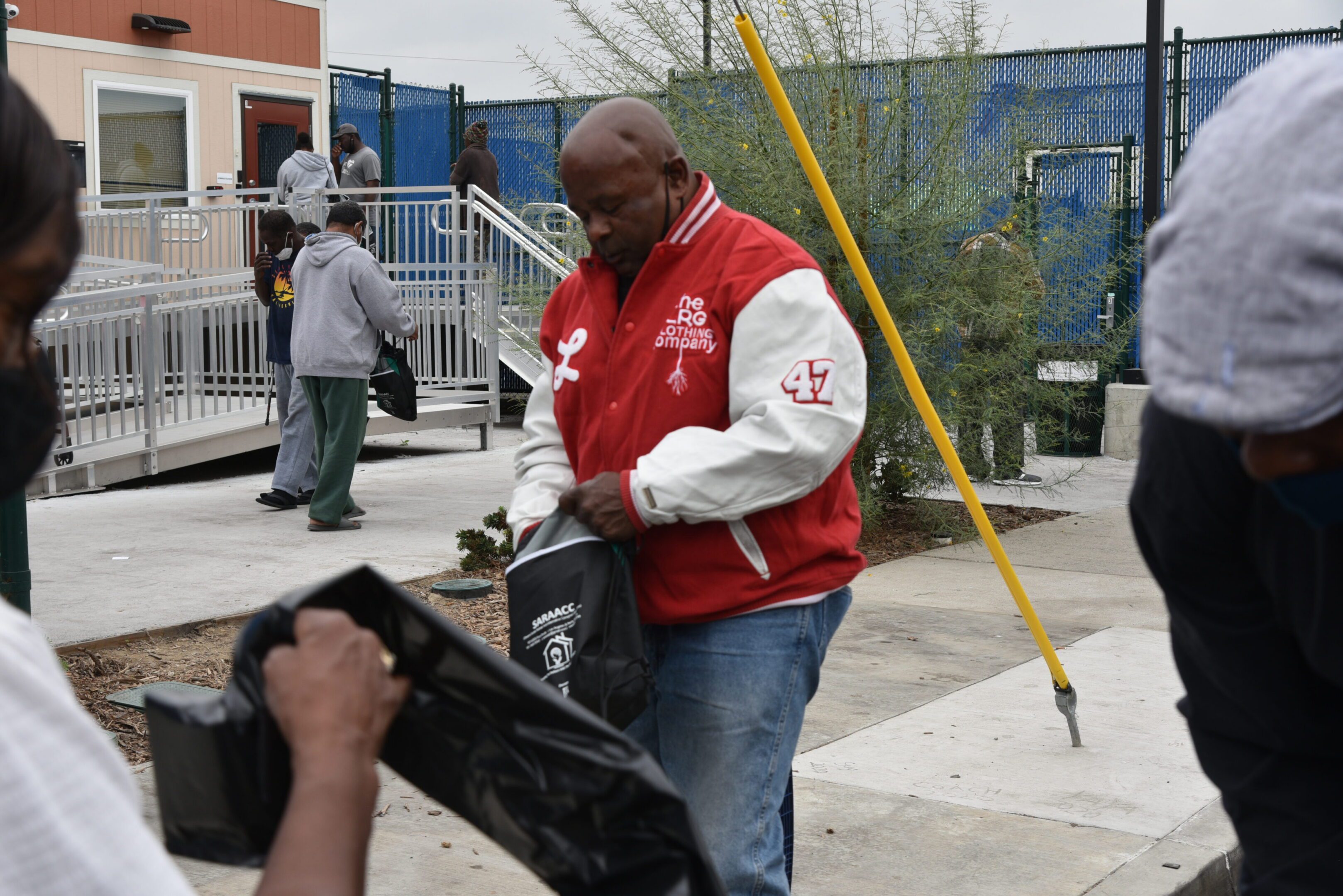 Man in red jacket holding a bag.