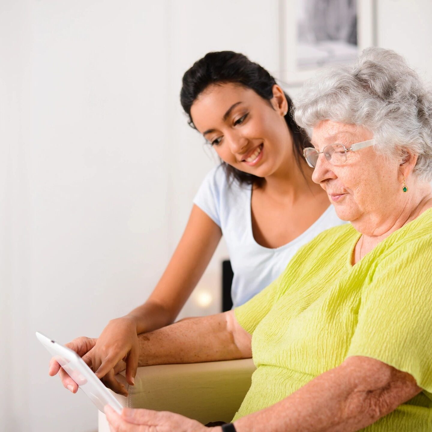 Elderly woman and caregiver with tablet.