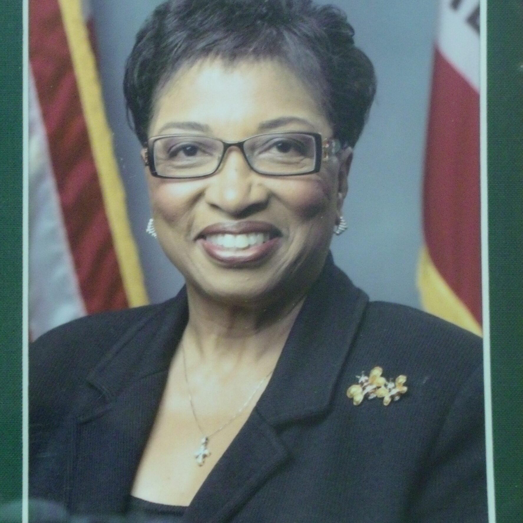 Smiling woman in formal attire with glasses.